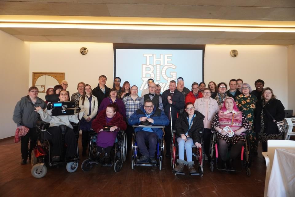 A group of people with physical and learning disabilities smiling